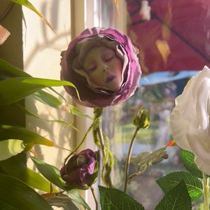 Potted purple and white fabric flower decoration with leafy green stems
