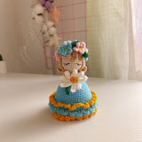 Crochet amigurumi bouquet doll with blue layered dress and flower hat, holding bouquet