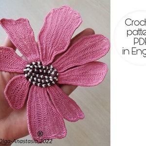 Pink 3D crochet flower motif with textured black-and-white center, close-up