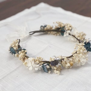 Dried flower crown halo wreath with ivory blooms and small teal accents on a fabric base