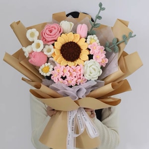 Handmade crochet flower bouquet with sunflower, pink and white blooms, wrapped in kraft paper