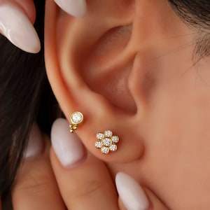 14k gold diamond flower stud earrings on an ear