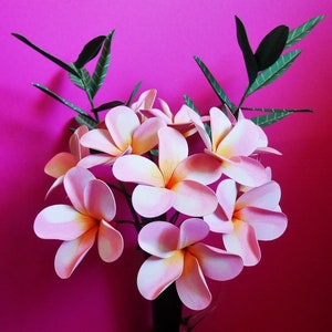 Pink paper flower bouquet with orange-yellow centers and green leaf stems
