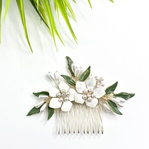 Floral pearl hair comb with white blossoms and green leaf accents, metal teeth