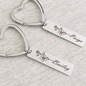 Silver metal keychain with engraved floral vines and the name 'Bailey' on a bar