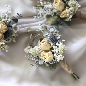 Dried flower sage boutonniere with cream roses, small white blooms, and green sprigs