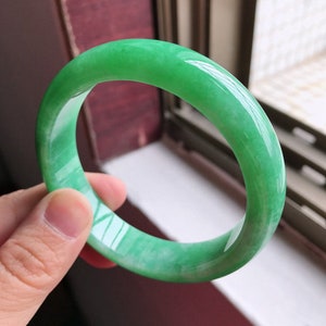 Light green jade round bangle with glossy finish and smooth hoop