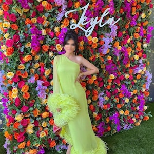 Artificial flower wall backdrop with multicolor roses; “Lyla” neon sign visible