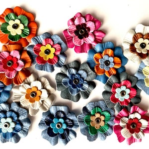 Assorted 1.5-inch soft leather flower embellishments in orange, blue, pink, and cream.