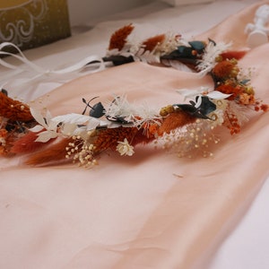 Dried flower crown with burnt orange blooms, white accents, and small leaf details