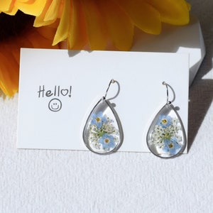 Pressed flower resin dangle earrings with silver teardrop frames and blue dried blooms