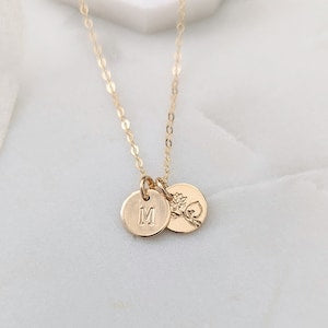 Gold birth flower necklace with round initial pendant and small floral charm