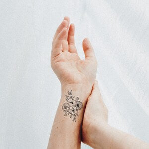 Floral birth flower tattoo drawing on wrist, delicate linework on skin
