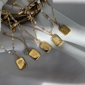 Gold square pendant necklace with small engraved symbols on link chain