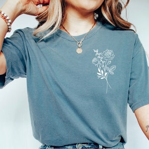 Teal short-sleeve T-shirt with white birth-flower tree graphic on the chest
