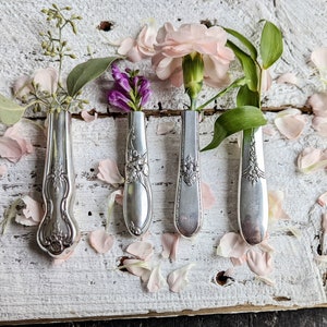 Metal vase-shaped refrigerator magnets holding small pink flowers and green leaves