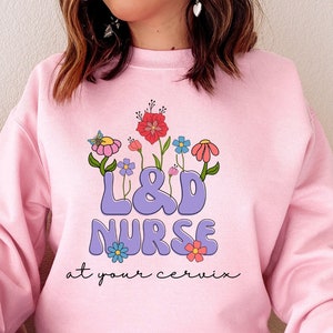 Pink L&D nurse sweatshirt with floral design and embroidered text on the chest