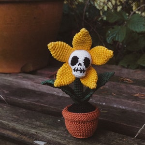 Crochet skull flower amigurumi in a small pot, yellow petals and green leaves