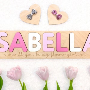 Wooden heart name puzzle reading 'SABELLA' and 'flower girl' text