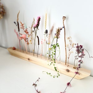 Dried floral centerpiece on wooden board with mixed stems and small blossoms