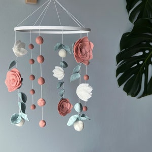 Felt baby crib mobile with pink and white flowers and green leaves hanging from hoop