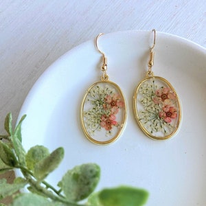 Oval pressed flower dangle earrings with gold-tone hooks and resin floral detailing