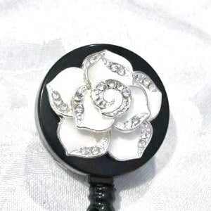 Flower retractable badge reel with black enamel case and silver flower detail