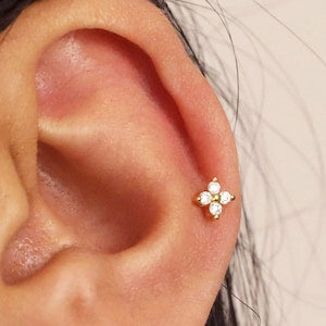 Sterling silver flat back labret stud with small flower design, worn in ear