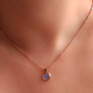 Small flower pendant necklace with blue resin centerpiece on a fine chain