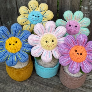 Crocheted amigurumi flower plush in small pots with smiling faces, pastel colors