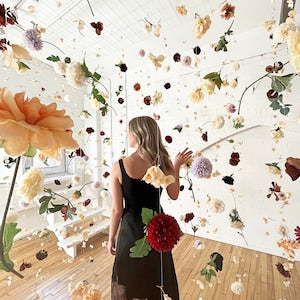 Hanging flower garland installation with red and pink blooms on floral wall backdrop