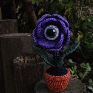 Crochet eye flower amigurumi plant decoration in pot, purple bloom, green leaves