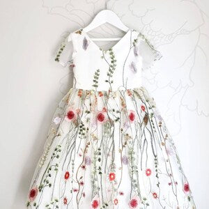 Embroidered floral flower girl dress with colorful blossoms on white fabric