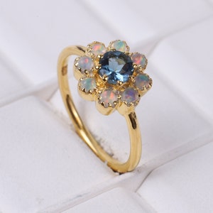 18K yellow gold flower ring with blue center gemstone and pastel side stones