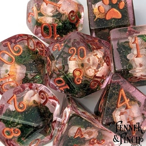 Floral polyhedral dice set with pink-green translucent dice and gold numbers, D20 and D4 visible