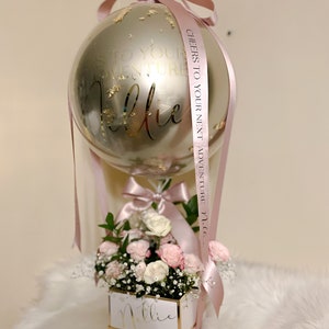 Hot air balloon flower arrangement with silver balloon, pink ribbon, and rose bouquet
