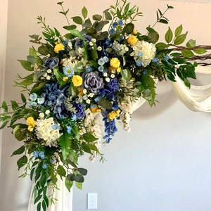 Wedding corner floral swag with blue, yellow, and white blooms and green foliage