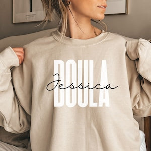 Personalized doula sweatshirt in light beige with “Jessica” and DOULA on front