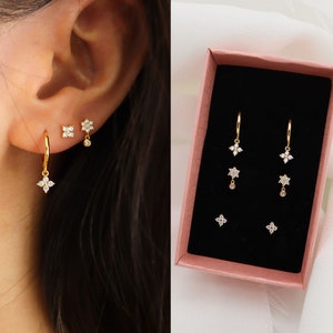 Gold four-leaf clover drop hoop earrings set with dangling clover charms