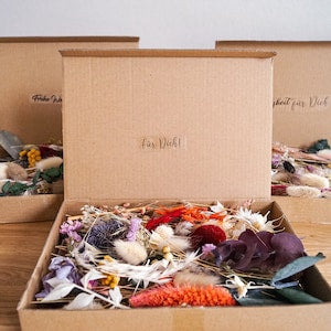 Dried flower mix in open cardboard box with multicolor dried blooms and petals
