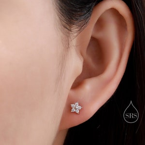 Tiny flower CZ stud earrings with clear stones in sterling silver, on-ear view