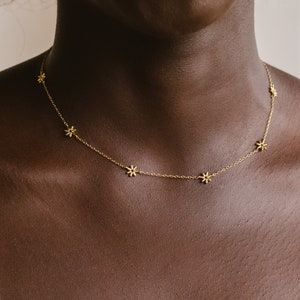Gold-tone flower charm choker necklace with small star-like accents