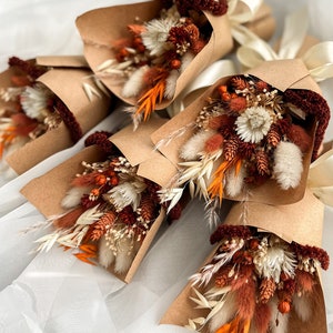 Mini dried flower bouquets with rust and white blooms, wrapped in kraft paper and tied ribbon