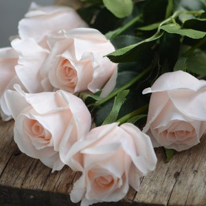 Pale pink artificial half-open roses with green leaves, realistic flower heads