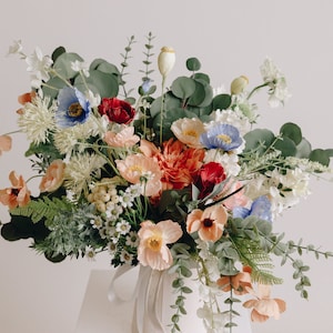 Artificial spring boho bouquet with mixed colorful flowers and green foliage, wrapped with ribbon