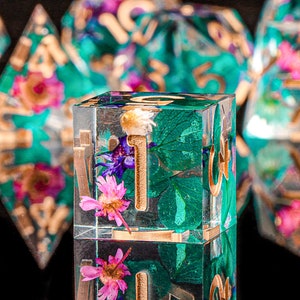 Green resin polyhedral dice with leaf and flower artwork and sharp edged faces
