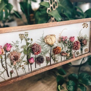 Framed dried flower wall art with pink and red blooms in a wood border