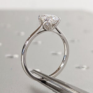 White gold tulip-style engagement ring with round center stone and floral prongs
