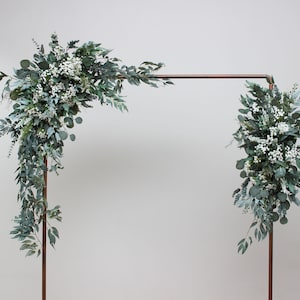 Faux baby's breath flower arch with leafy greenery and small white blooms on a metal frame