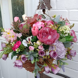 Artificial hanging flower basket with pink and purple faux blooms and green leaves